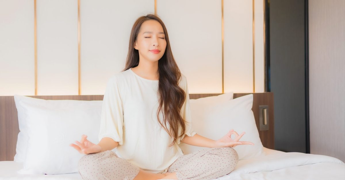 Portrait beautiful young asian woman meditation on bed in bedroom interior