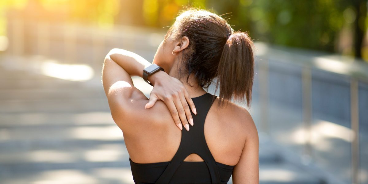 運動後背肌緊繃的女性正在揉按肩胛位置，呈現背肌疲勞與啟動不足的情況。