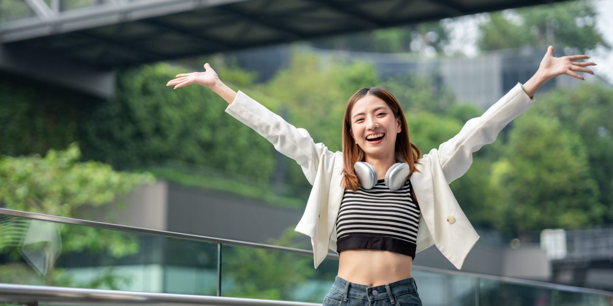 年輕亞洲女性在城市戶外張開雙臂開心微笑，展現輕盈體態與菲斯波拉提後的自信神情